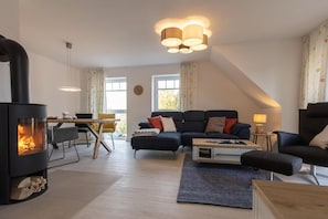 Un salon moderne avec une cheminée, un canapé, une table basse et un coin repas.