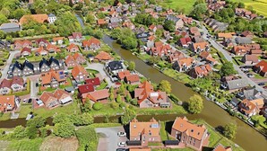 An aerial view of a residential area with houses, a river, and a parking lot.