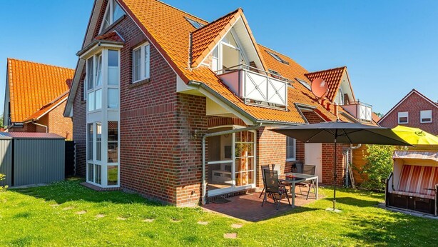 A two-story house with a sloped roof, a visible attic, and a patio area with outdoor furniture.