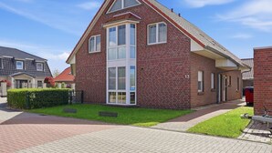 A two-story house with a prominent central window, a brick facade, and a small front yard.