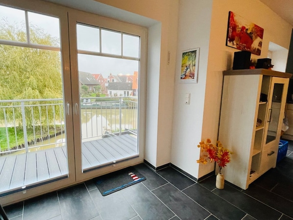 Ein Zimmer mit einer Schiebetür zum Balkon, einem kleinen Schrank und einem gerahmten Bild an der Wand.