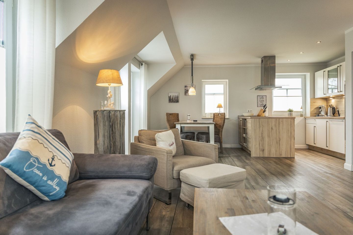 Una sala moderna con un sofá, un reposapiés y un comedor con una mesa y sillas.