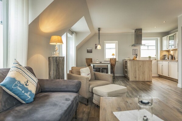 Una sala moderna con un sofá, un reposapiés y un comedor con una mesa y sillas.