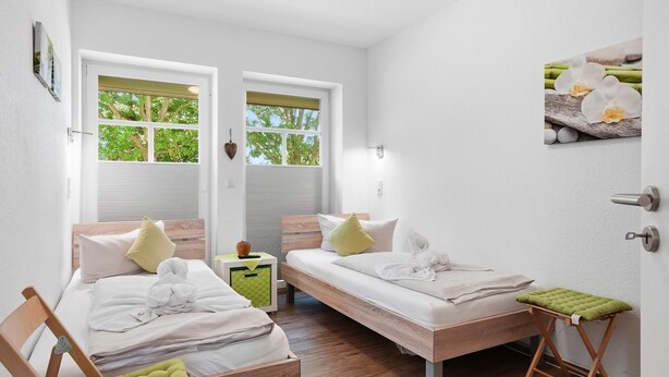 Une chambre avec deux lits, une petite table et un banc.