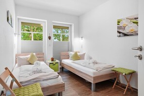 Une chambre avec deux lits, une petite table et un banc.