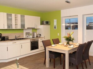 A modern kitchen with white cabinets, a microwave, and a dining area with a wooden table and chairs.