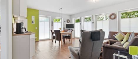 Una sala de estar moderna con un sofá, una mesa de comedor y una zona de cocina con una cafetera.