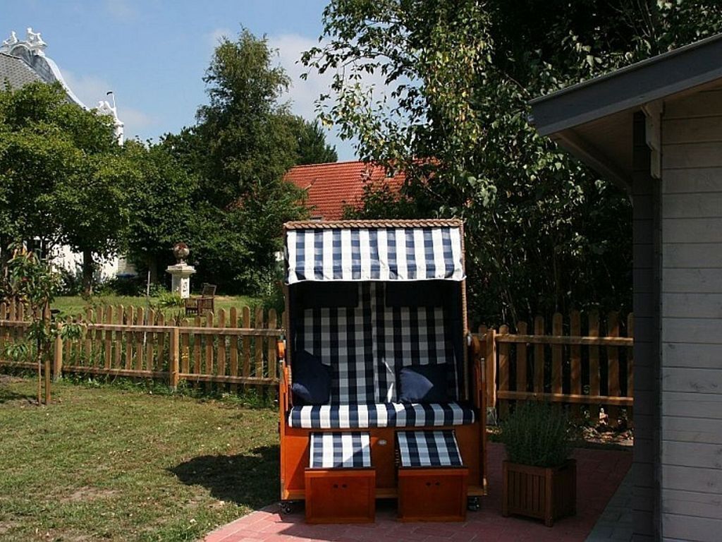 A checkered outdoor seating area with a canopy, surrounded by a wooden fence and greenery.