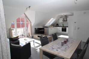 A modern apartment with a dining area, kitchen, and a balcony with a view. - Kyana - Schöne Ferienwohnung in Ruhiger Lage von Norden (Norden)
