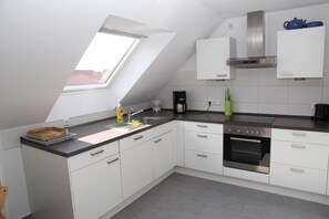 A modern kitchen with white cabinets, a built-in oven, and a skylight. - Kyana - Schöne Ferienwohnung in Ruhiger Lage von Norden (Norden)