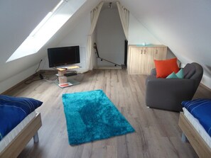 A small, well-lit attic room with a television, a desk, a chair, and a sofa. - Kyana - Schöne Ferienwohnung in Ruhiger Lage von Norden (Norden)