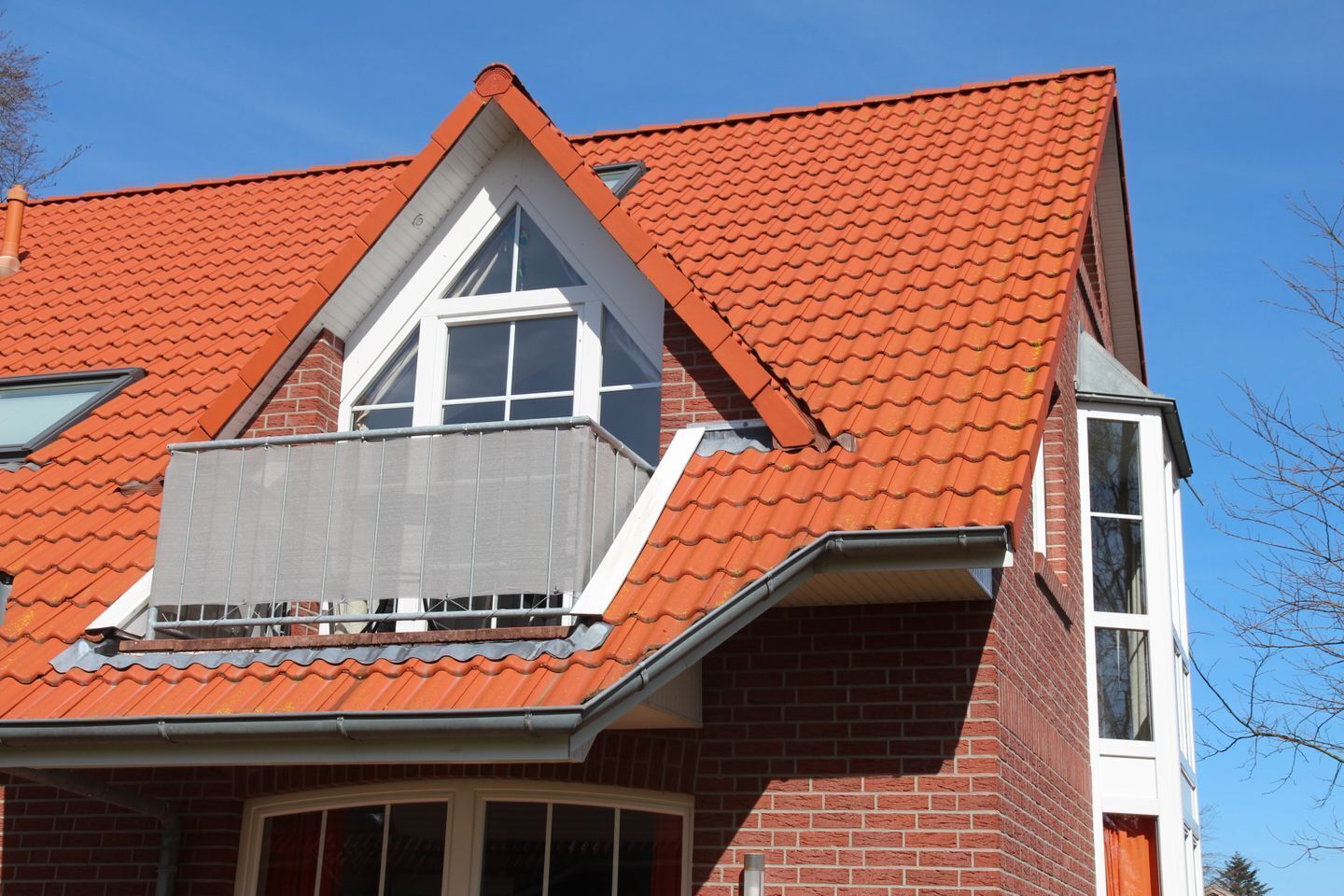 A red-tiled roof with a dormer window and a visible chimney.
