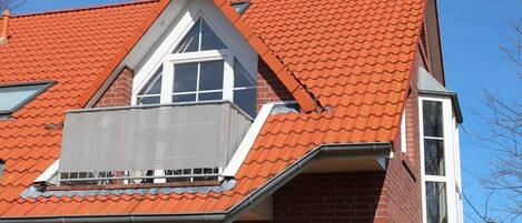 A red-tiled roof with a dormer window and a visible chimney.