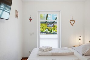 Un dormitorio con cama, ventana, luz empotrada en la pared y decoración con forma de corazón.
