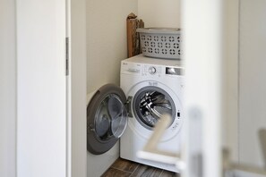 Un espace buanderie équipé d’un lave-linge à chargement frontal et d’un sèche-linge.