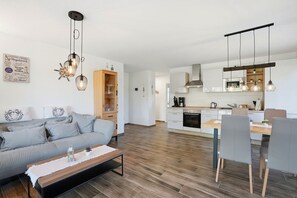 Une cuisine moderne avec des meubles blancs, un four encastré et un coin repas comprenant une table et des chaises en bois.