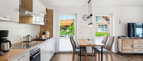 Una cocina moderna con comedor, armarios de madera y vistas al exterior.