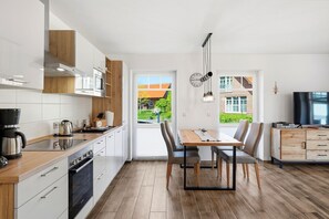 Eine moderne Küche mit Essbereich, Holzschränken und Blick ins Freie.