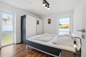 A modern bedroom with a bed, bedside tables, a wardrobe, and a window.