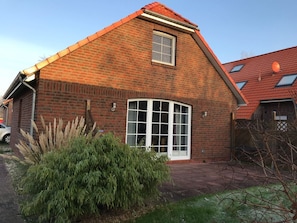 A brick house with a red roof, a large window, and a small satellite dish. - Achtern Diek - Holiday home with 100sqm for up to 6 persons with 2 bathrooms and (Norden)