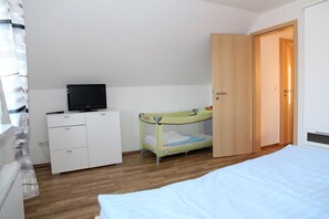 A bedroom with a bunk bed, a desk with a TV, and a wardrobe.