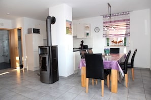 A modern kitchen with a built-in stove, dining table with chairs, and a clock on the wall. - Achtern Diek - Holiday home with 100sqm for up to 6 persons with 2 bathrooms and (Norden)