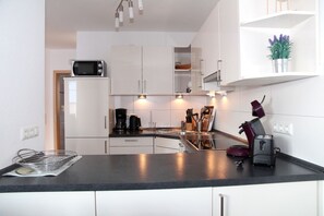 A modern kitchen with white cabinets, a black countertop, and a built-in microwave. - Achtern Diek - Holiday home with 100sqm for up to 6 persons with 2 bathrooms and (Norden)