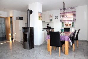A modern kitchen with a built-in stove, dining table with chairs, and a clock on the wall.