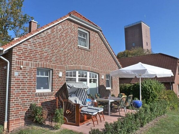 A brick house with a patio area featuring outdoor furniture and a white umbrella.