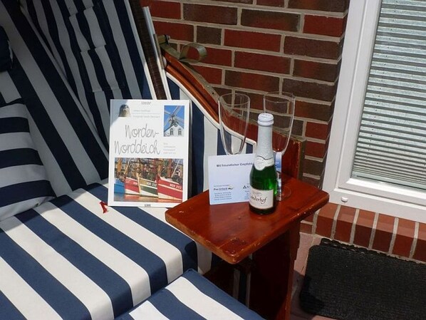 A striped sofa, a small wooden table with a bottle of champagne, and a framed picture of a windmill.