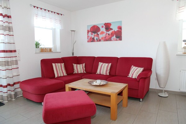 A red sofa set with striped pillows, a wooden coffee table, and a radiator.