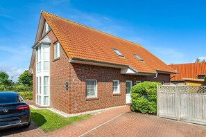 Ein zweistöckiges Backsteinhaus mit geneigtem Dach, einer sichtbaren Garagentür und einem gepflegten Rasen.