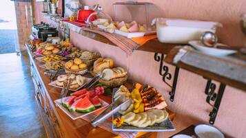 Een buffet met diverse soorten eten, zoals brood, gebak, fruit en groenten.