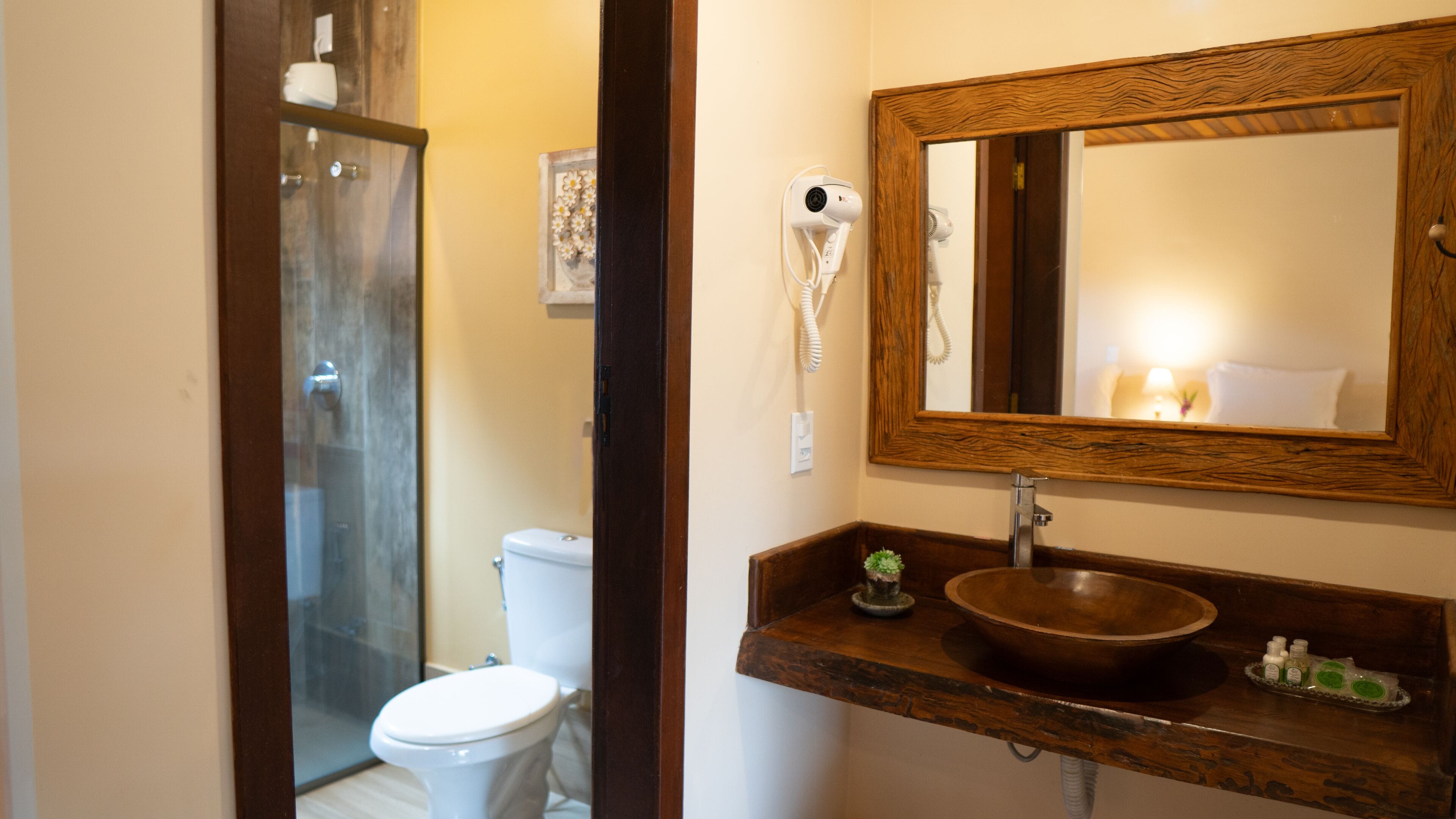 A bathroom with a wooden vanity, a large mirror, a white toilet, and a glass shower enclosure.