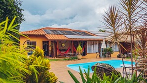 A house with a swimming pool, solar panels, and outdoor furniture. - Pousada Lua Clara (Alto Paraíso de Goiás)
