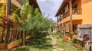 A courtyard with a stone pathway, surrounded by lush greenery and banana trees. - Pousada Lua Clara (Alto Paraíso de Goiás)