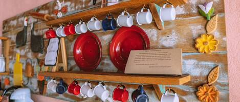 A wall with shelves holding various mugs and plates, a sign with text, and decorative items.