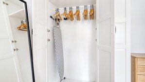 Ein begehbarer Kleiderschrank mit einem Spiegelkleidungsstück, Holzaufhängern und einem Drahtgittervorhang.