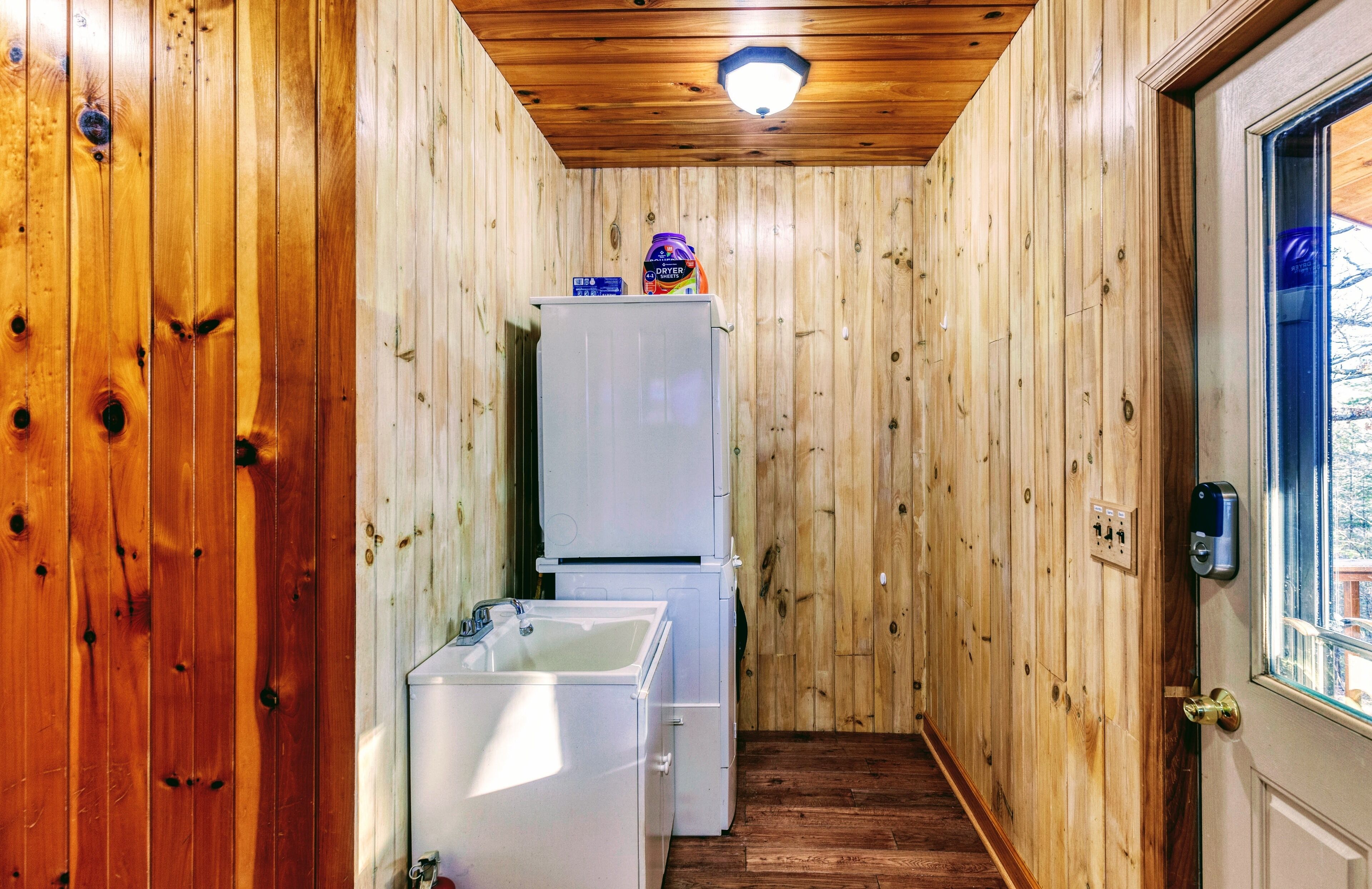 A narrow hallway with wooden walls, a white refrigerator, and a sink.