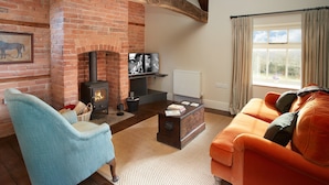 A living room with a brick fireplace, a sofa, a chair, and a television. - A romantic getaway, with access to the well known Mortimer Walking Trail.  (Leominster)