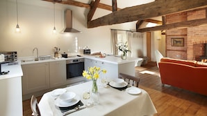 A kitchen with a central island, a dining table set for four, and a red sofa in the living area. - A romantic getaway, with access to the well known Mortimer Walking Trail.  (Leominster)