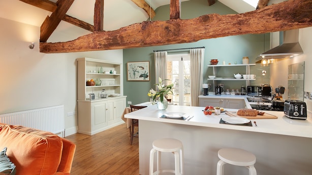 A kitchen with a central island, white bar stools, wooden beams, and a view to the dining area. - A romantic getaway, with access to the well known Mortimer Walking Trail.  (Leominster)