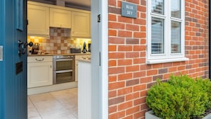 A modern kitchen with white cabinets, a brick exterior, and a sign reading "BLUE SKY". - Blue Sky, Wells-next-the-Sea, Norfolk (Wells-next-the-Sea)
