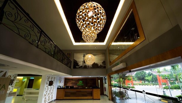A hotel lobby with a reception desk, a large decorative light fixture, and a staircase. - De Palma Resort Kuala Selangor (Kuala Selangor)