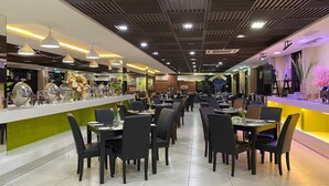 A modern restaurant with a long counter, black chairs, and a green accent wall. - De Palma Resort Kuala Selangor (Kuala Selangor)