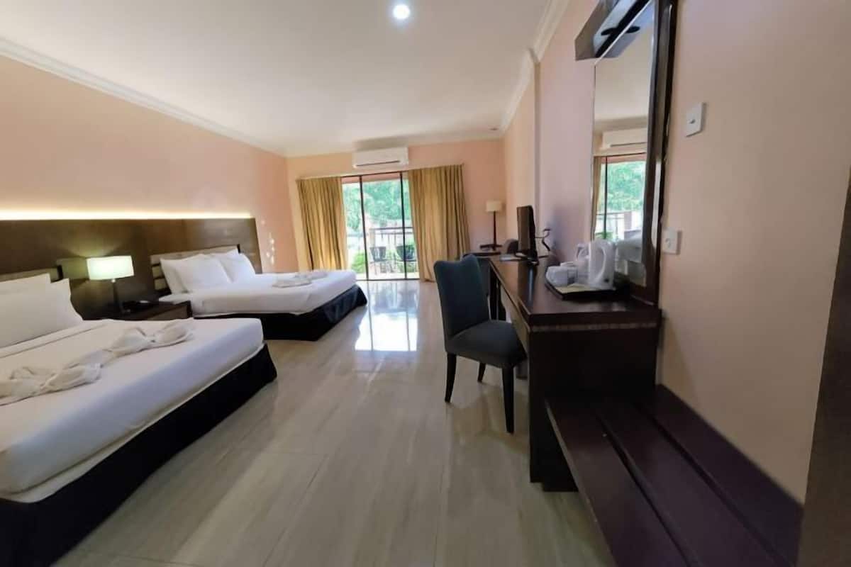 Ein Hotelzimmer mit zwei Betten, einem Schreibtisch, einem Stuhl und einem großen Fenster mit Vorhängen.