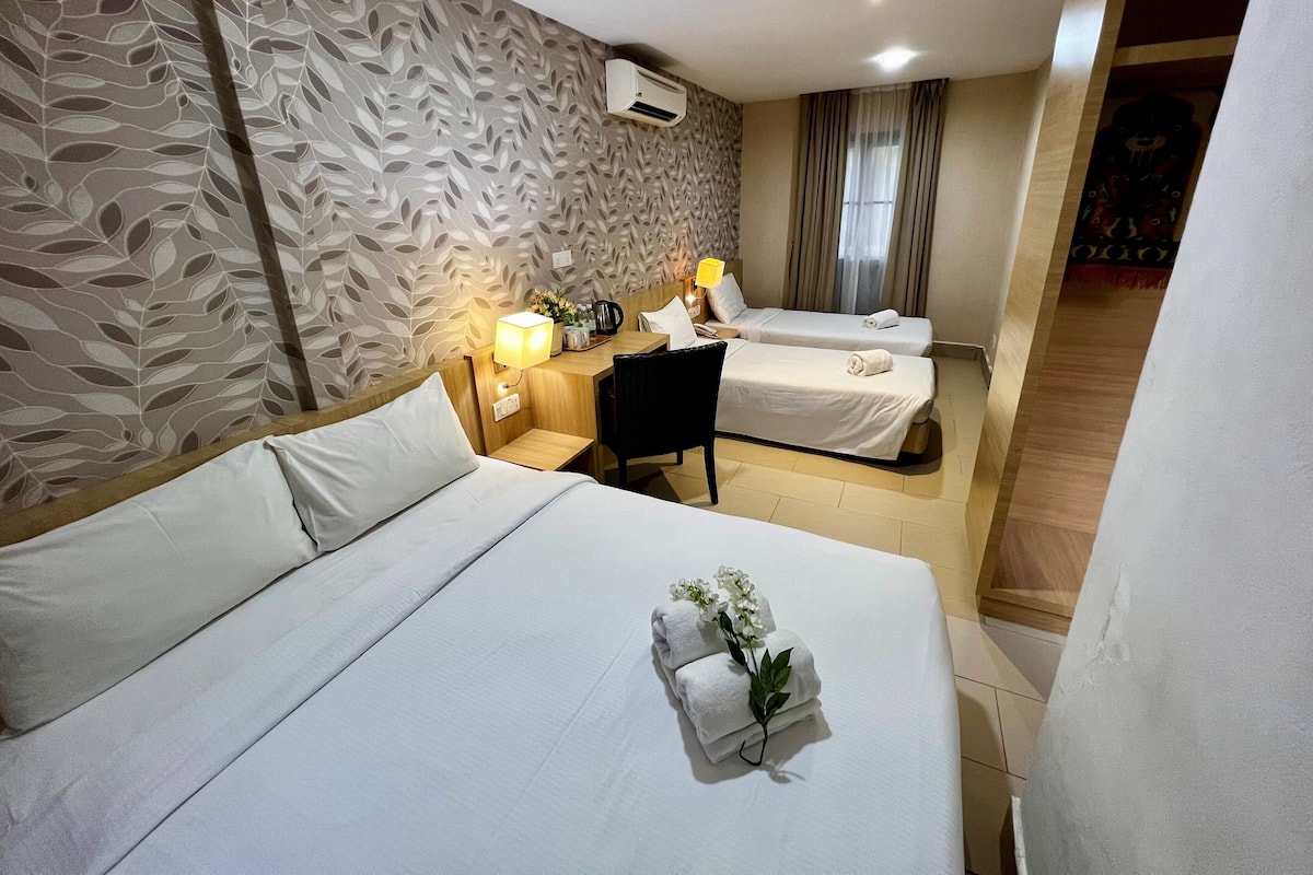 Ein Hotelzimmer mit zwei Betten, einem Schreibtisch, einem Stuhl, einer Lampe und einer Zimmerpflanze.