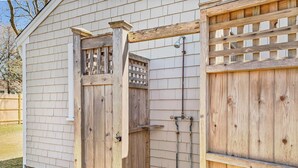 A wooden gate with a latch and a small window, attached to a house with siding. - Turtle Cove Cottage: Steps to Long Pond Beach (South Yarmouth)