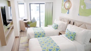 A hotel room with two beds, a TV, a desk, and a view of the outside.