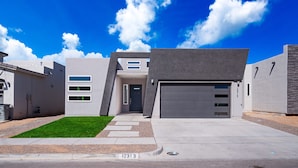 Ein modernes Wohngebäude mit Garage, gepflegtem Rasen und blauem Himmel.